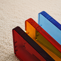 Close-up of translucent thick acrylic side panels in orange, red and blue, texture shot of modular pet feeding stand parts