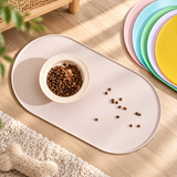 Pastel silicone pet feeding mat with dog food bowl spilled kibble on wooden floor