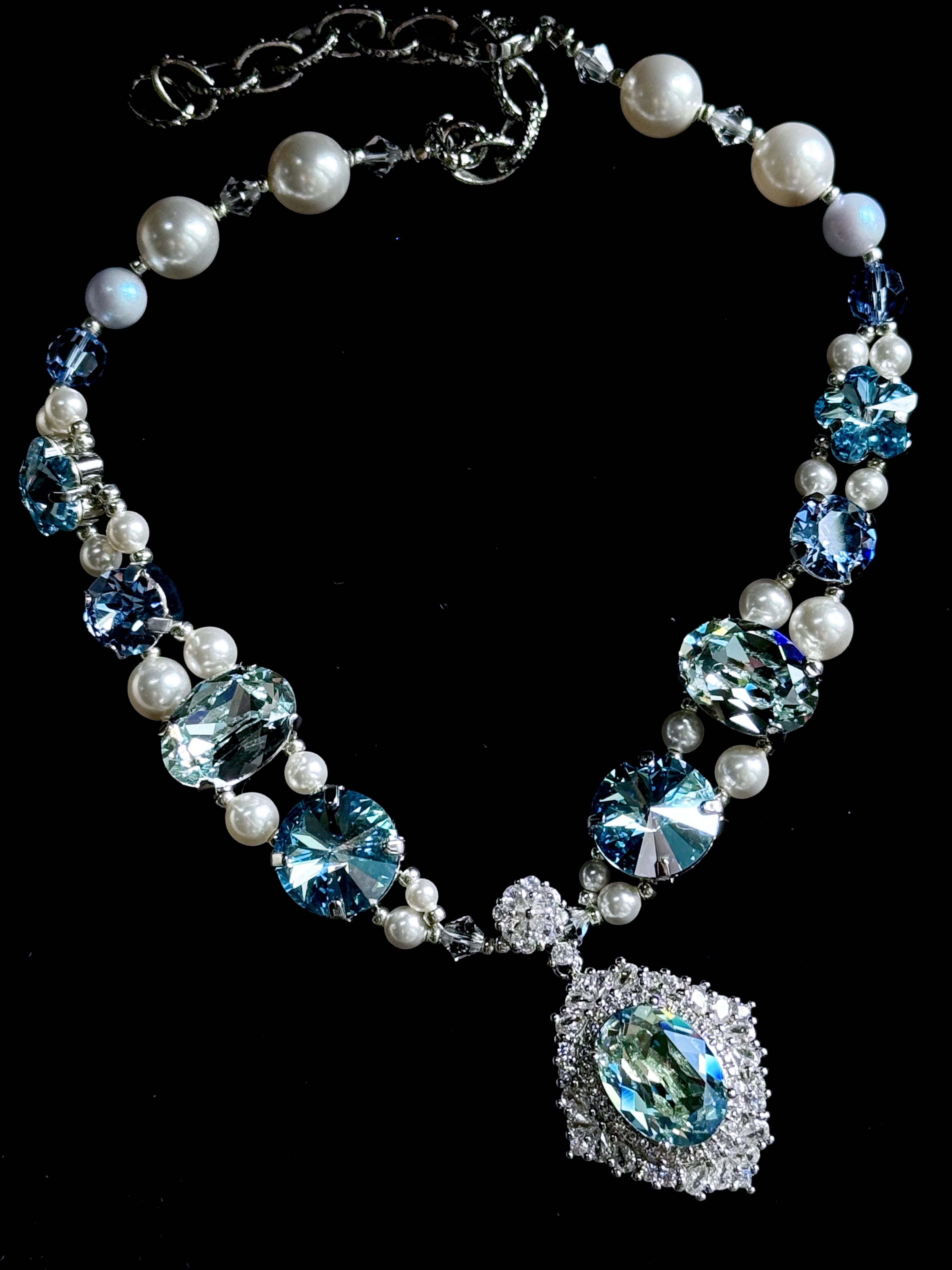 Top-down view of ocean blue crystal pearl dog choker, mixed shape sparkling gems, statement aquamarine pendant, fancy pet party jewelry