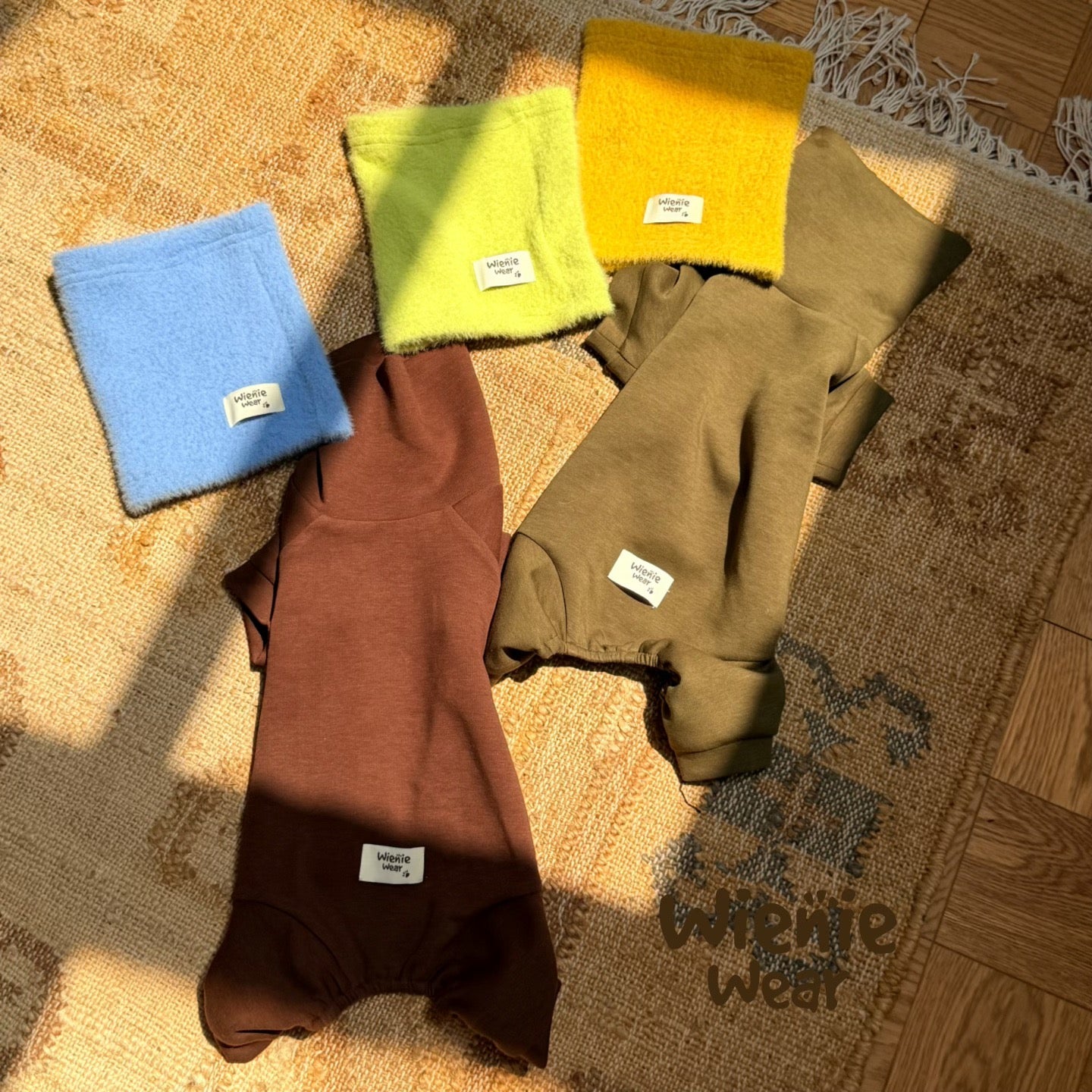 Flat lay of dachshund fleece jumpsuit in multiple colors blue brown olive green yellow dog pajama color swatches