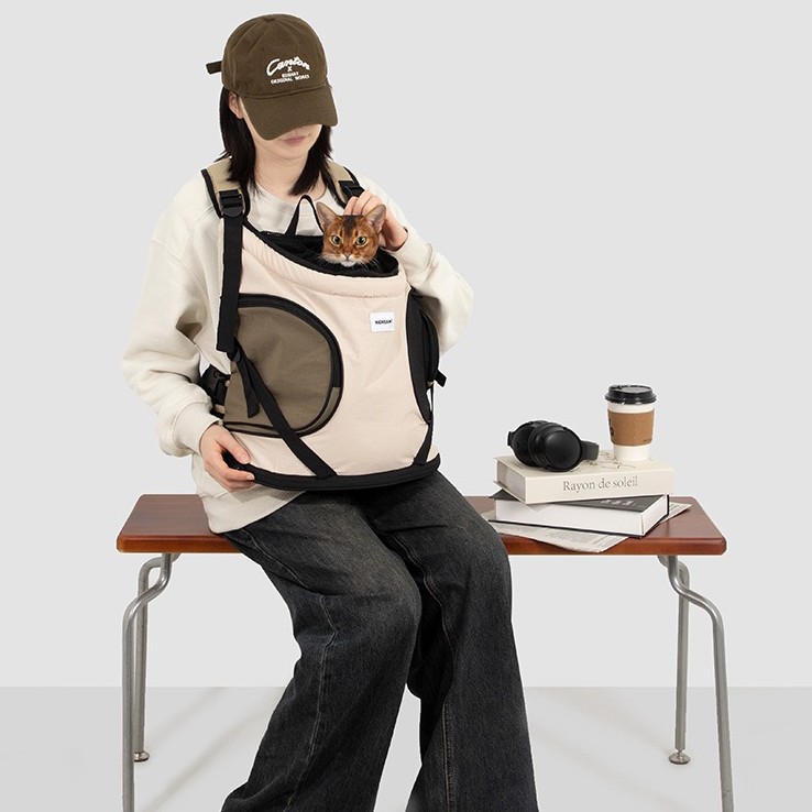 ront-carry-pet-backpack-carrier-beige-khaki-cat, Woman sitting on bench wearing front carry pet backpack carrier, cat peeking out, breathable mesh pet front carrier for cats and small dogs